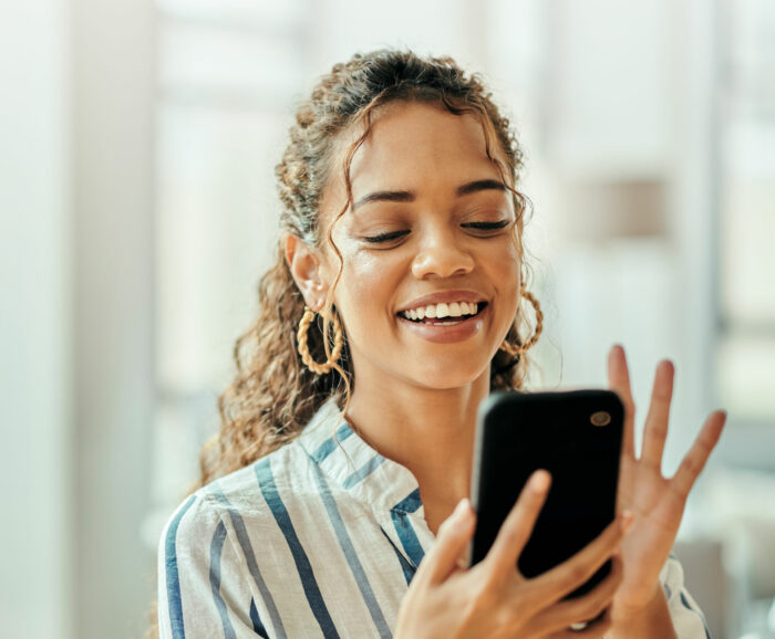 Woman waving at somebody on her phone