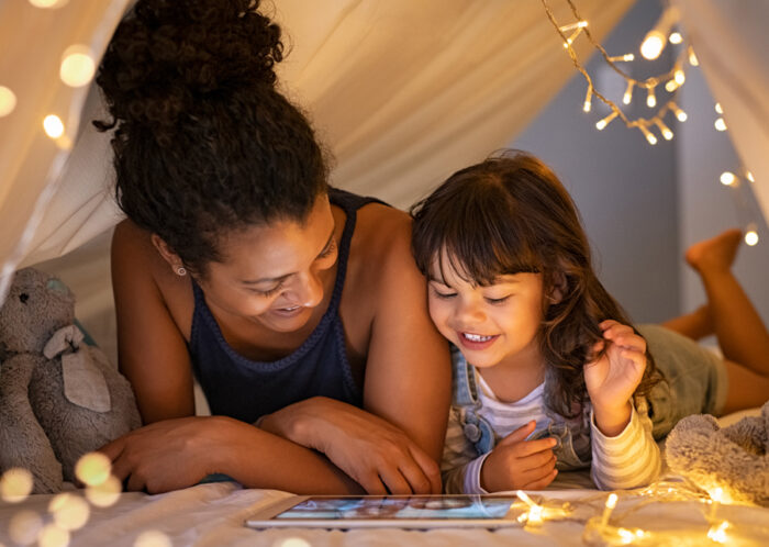 Woman and child bent over a tablet in a tent