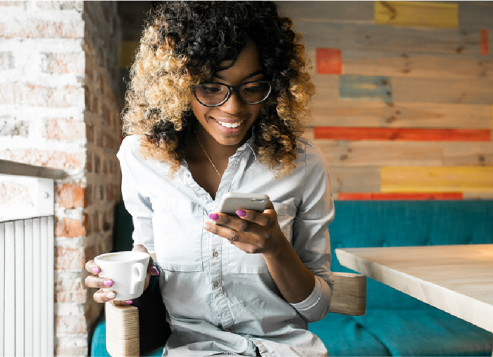 Lady looking at phone while enjoying coffee.